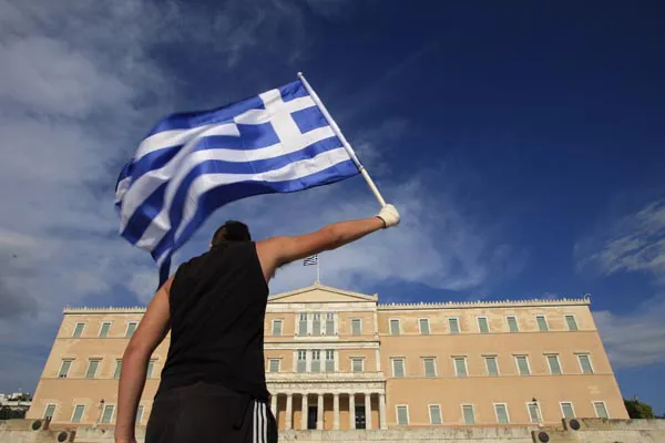 A protester raises Greek flag in front of the parliament during a rally against a new austerity package at Athens' Syntagma square