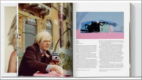 Andy Warhol sostiene su cámara Polaroid y muestra una de sus fotografías.