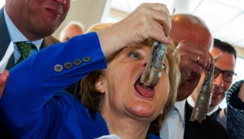 Fotografá insólita de angela Merkel probando un un tentempié recién capturado en el Mar Báltico.