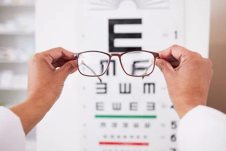 208289395-glasses-in-hands-optometry-and-vision-eye-care-and-health-with-eyesight-test-and-chart